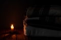 A blanket and a pillow folded in a stack on a background of fire candles in a dark bedroom Royalty Free Stock Photo
