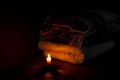 A blanket and a pillow folded in a stack on a background of fire candles in a dark bedroom Royalty Free Stock Photo