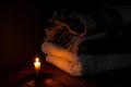 A blanket and a pillow folded in a stack on a background of fire candles in a dark bedroom