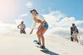 Blasting down the dunes. a young woman sand boarding in the desert.