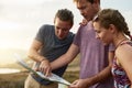 Blazing brave new trails together. three young hikers consulting a map while exploring a new trail. Royalty Free Stock Photo