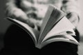 Bleak black and white colors of an open book in the hands of a reader with blurred background Royalty Free Stock Photo