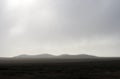 A bleak moody landscape of distance mountains rising from moorland on a winters day. Outer Hebrides. Scotland, UK
