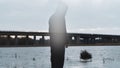 A bleak, moody, winter edit of a ghostly transparent hooded figure vanishing and standing next to a lake, looking out to a