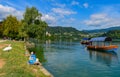 Two girls and a goose sit on the shore and look at the traditional Slovenian boats