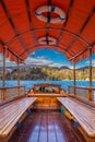 Bled, Slovenia - Traditional wooden red canvas roof Pletna boat at Lake Bled on a sunny autumn day with Julian Alps at background Royalty Free Stock Photo