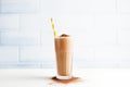 blended chocolate milkshake in tall glass with straw