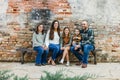 Blended family of five with two girls and a baby boy sitting on a table by an urban old brick wall Royalty Free Stock Photo