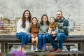 Blended family of five with two girls and a baby boy sitting on a table by an urban old brick wall Royalty Free Stock Photo