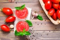 Blended fresh tomato juice with basil leaves in glasses and ingredients for its preparation on a wooden table Royalty Free Stock Photo
