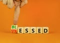 Blessed or stressed symbol. Businessman turns wooden cubes and changes the concept word Stressed to Blessed. Beautiful orange