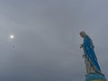 Blessed Virgin Mary, mother of Jesus, statue over dark sky background with the sun Royalty Free Stock Photo