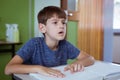 Blind caucasian schoolboy sitting at desk in classroom reading braille book with fingers