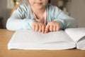 Blind child reading book written in Braille at table