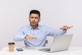 Blind disoriented man employee sitting office workplace, outstretching hands trying to find laptop on desk