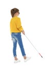 Blind girl with long cane walking on white