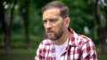 Blind man sitting on bench in park, feeling despair and helplessness, awareness