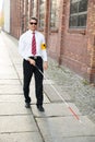 Blind man walking on sidewalk holding stick