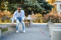 Blind man with a walking stick sitting on a bench at a park Royalty Free Stock Photo