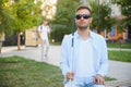 Blind man with a walking stick sitting on a bench at a park Royalty Free Stock Photo