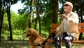 Blind pensioner preparing to stand up from bench, holding guide dog to walk park Royalty Free Stock Photo