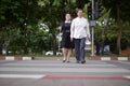 Blind person Asian woman with white cane crossing street walking on crosswalk with the sighted guide person senior woman by Royalty Free Stock Photo