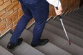 Blind person with long cane going down stairs Royalty Free Stock Photo