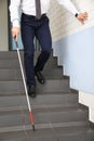 Blind person with long cane going down stairs Royalty Free Stock Photo