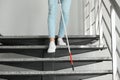 Blind person with long cane going down stairs indoors Royalty Free Stock Photo