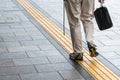 Blind unrecognizable person walking on a tactile paving path, rear view, outdoors