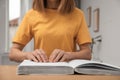 Blind woman reading book written in Braille at table