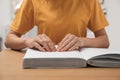 Blind woman reading book written in Braille at table