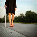 Blind woman walking on city streets, using her white cane