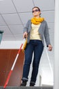 Blind woman walking down stairs alone using cane