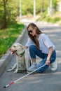 Blind young woman cuddling with guide dog on a walk outdoors. Royalty Free Stock Photo