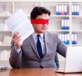 Blindfold businessman sitting at desk in office Royalty Free Stock Photo