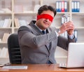 Blindfold businessman sitting at desk in office Royalty Free Stock Photo