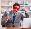 Blindfold businessman sitting at desk in office Royalty Free Stock Photo