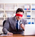 Blindfold businessman sitting at desk in office Royalty Free Stock Photo