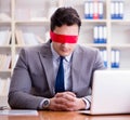 Blindfold businessman sitting at desk in office Royalty Free Stock Photo