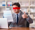 Blindfold businessman sitting at desk in office Royalty Free Stock Photo