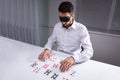 Blindfolded Businessman Reading Cards In Office