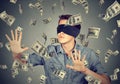 Blindfolded man trying to catch dollar bills banknotes flying in air Royalty Free Stock Photo