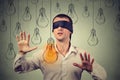 Blindfolded man walking through light bulbs searching for bright idea Royalty Free Stock Photo