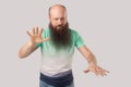 Blindness. Portrait of middle aged bald man with beard in light green t-shirt standing with closed eyes and trying to touching or Royalty Free Stock Photo