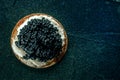 A blini with caviar and cream cheese, shot from above on black