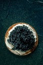A blini with caviar and cream cheese, shot from the top on black