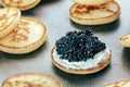Blinis with black caviar and cream cheese, on a festive dish, mini pancakes