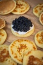 Blinis with black caviar and cream cheese, on a festive dish, mini pancakes, an elegant appetizer