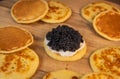 Blinis with black caviar and cream cheese, on a festive dish, mini pancakes, an elegant appetizer